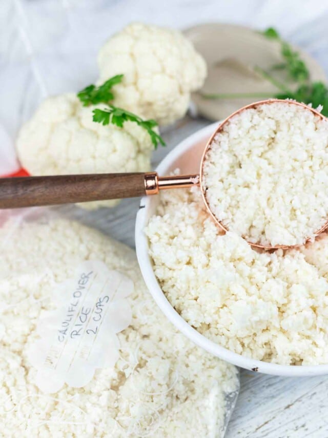 Cauliflower rice in a bowl next to a spoon.