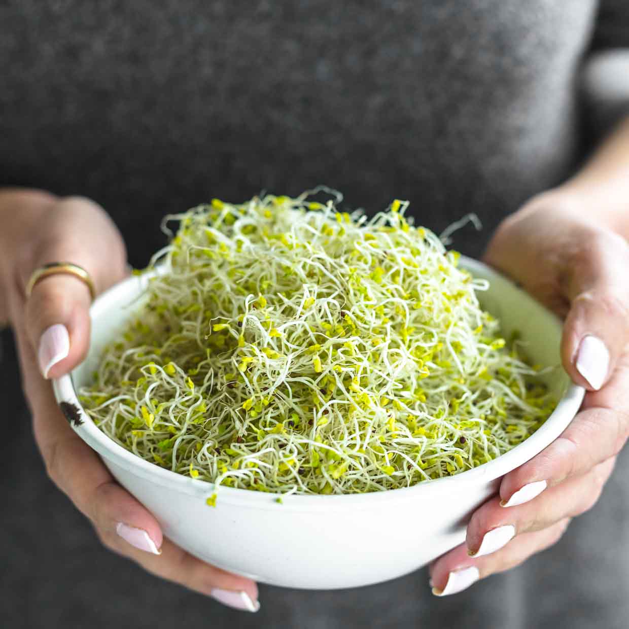 A woman holding a bowl of sprouts.