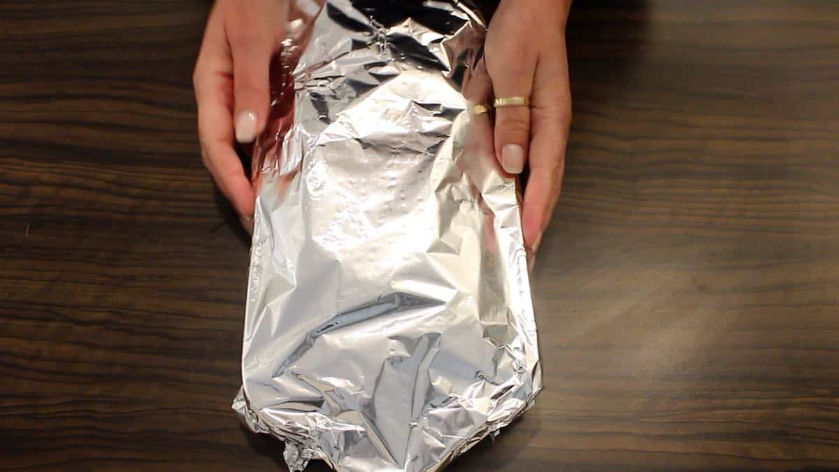 Covering casserole with a piece of foil on a table.