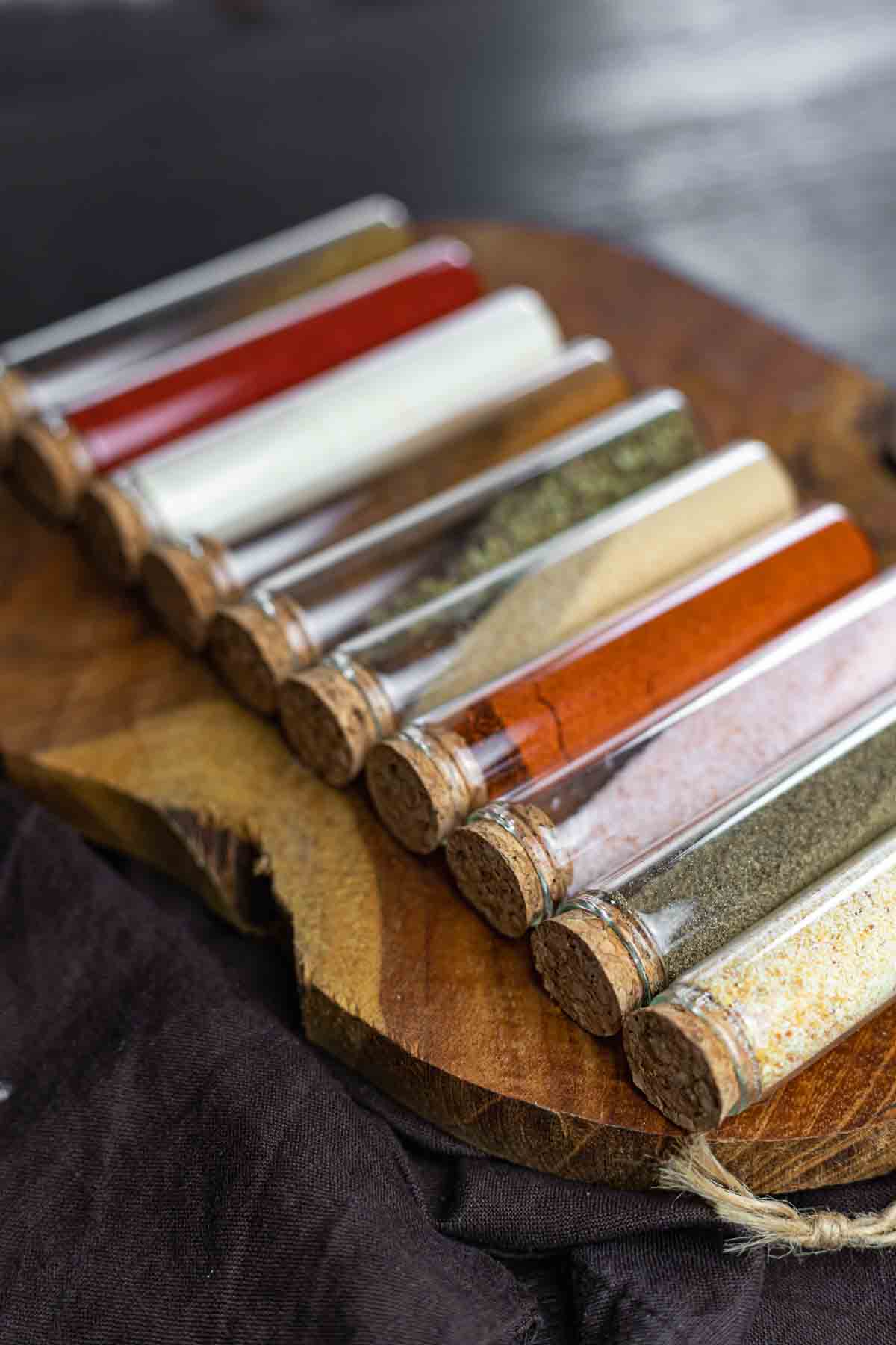A set of spice jars on a wooden cutting board.