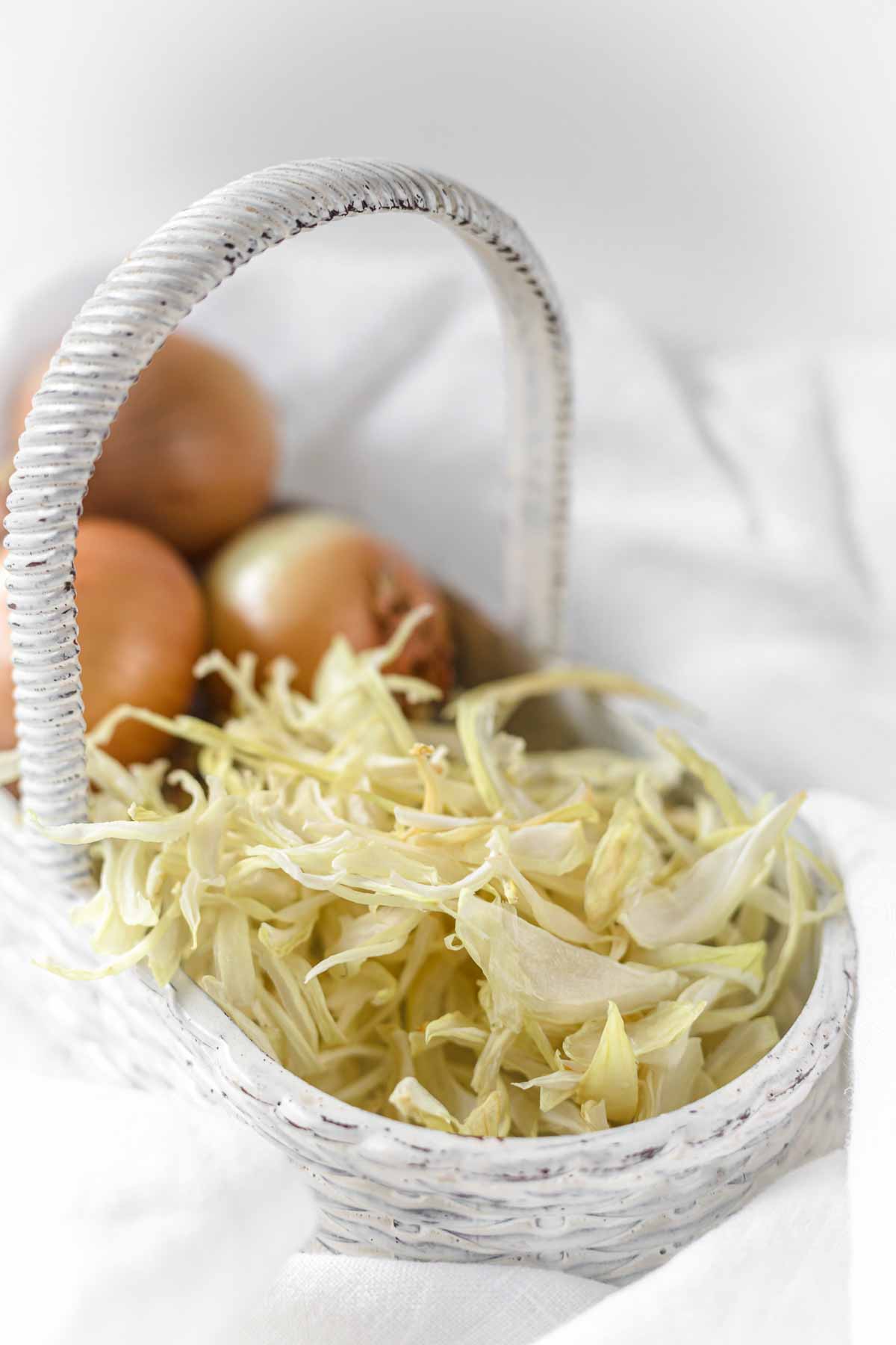 A wicker basket with onions in it.