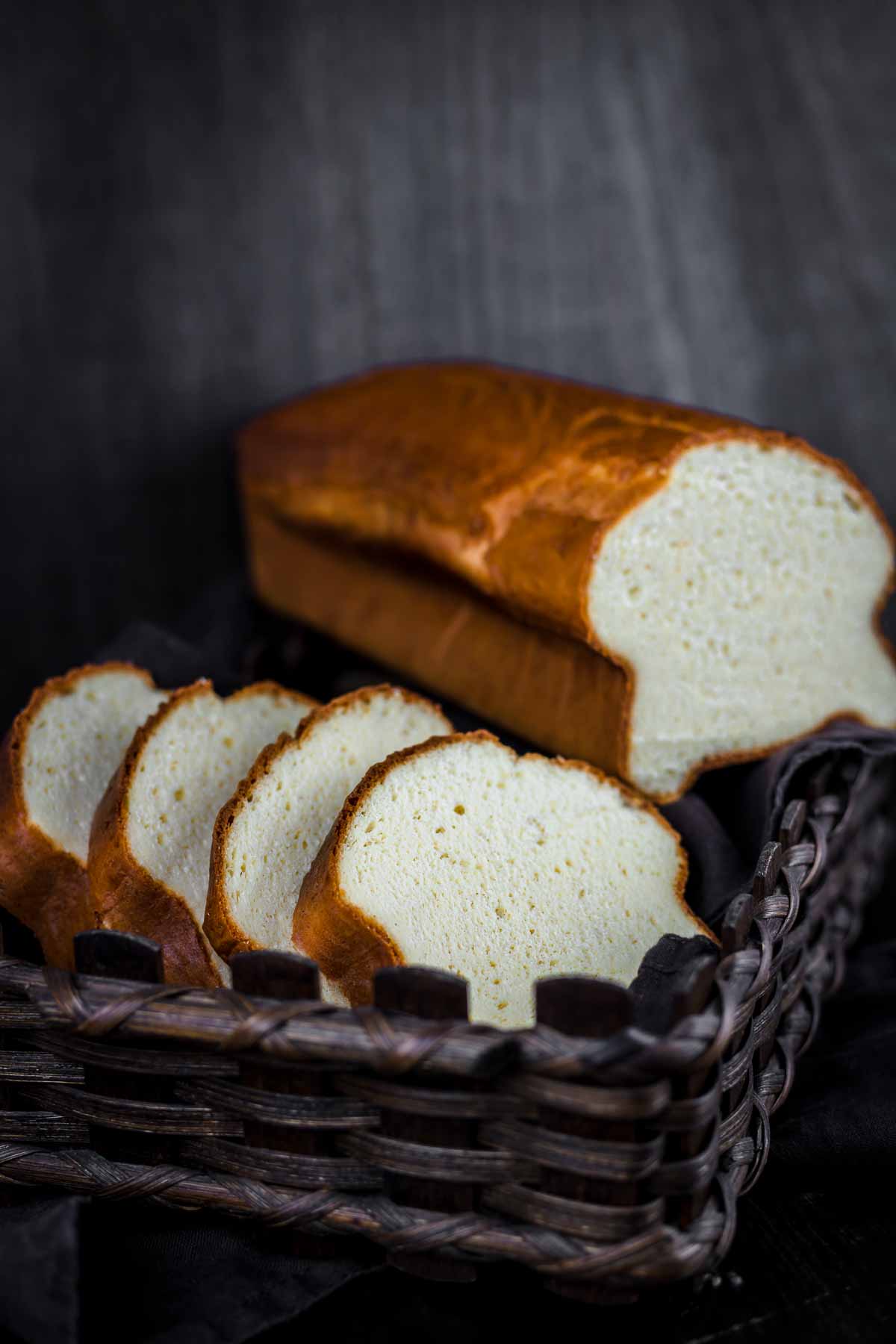A loaf of Protein Bread in a basket on a black background.