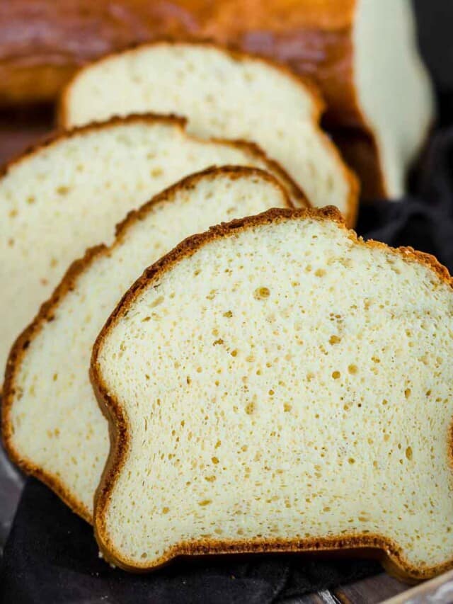 A loaf of white bread is sliced and placed on a plate.