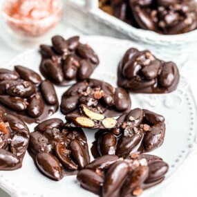 Chocolate covered almonds on a white plate.