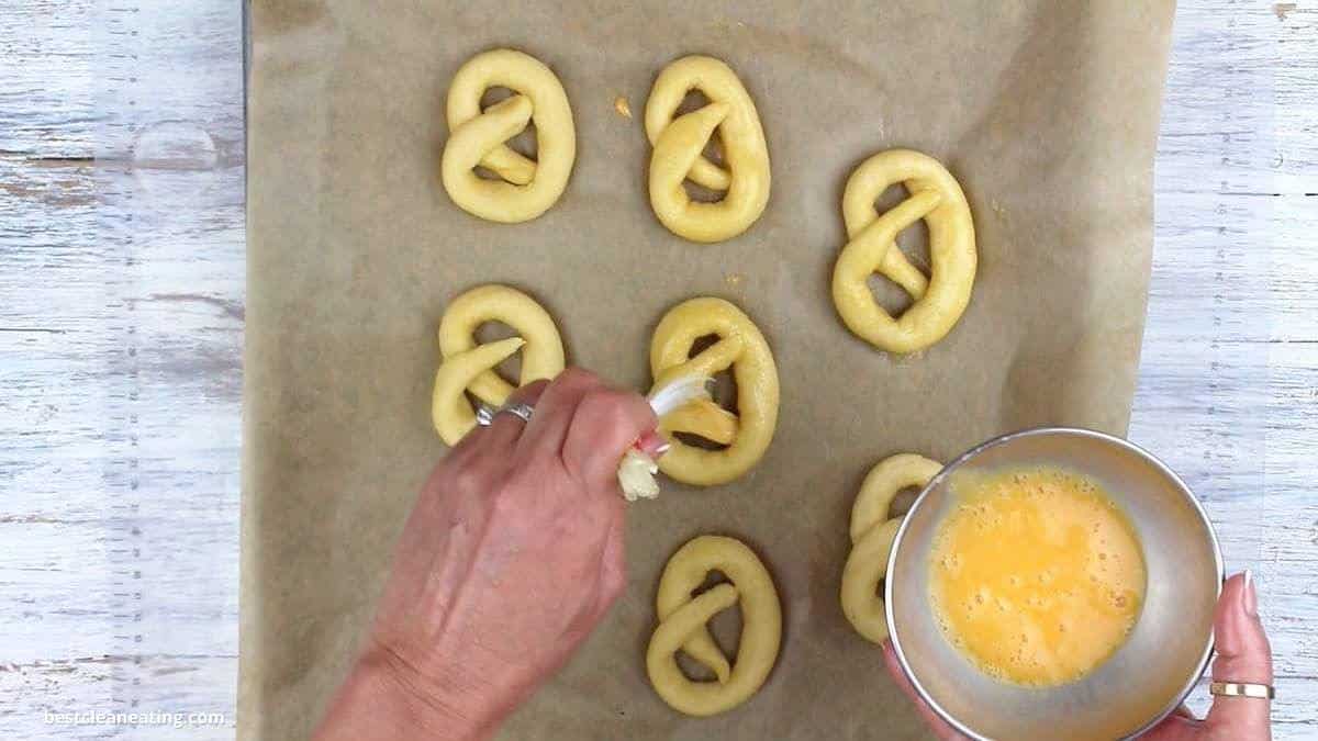 Spreading egg wash on pretzel.