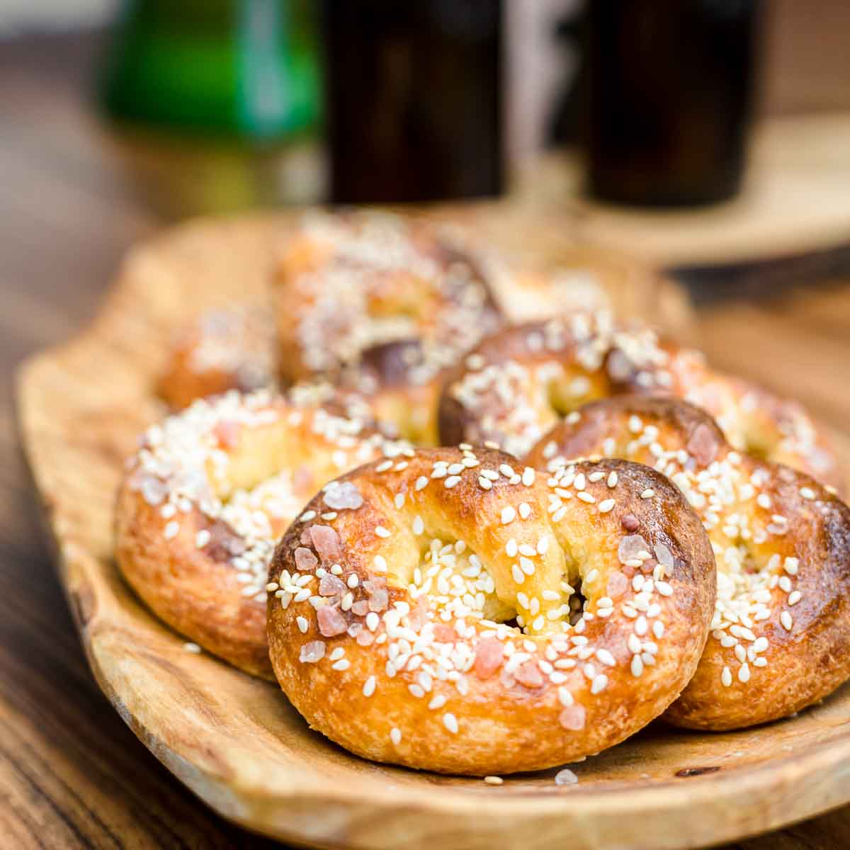 Pretzels with sesame seeds on a wooden plate.
