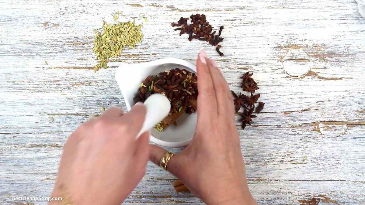 Grinding spices in a mortar and pestle on a wooden surface.