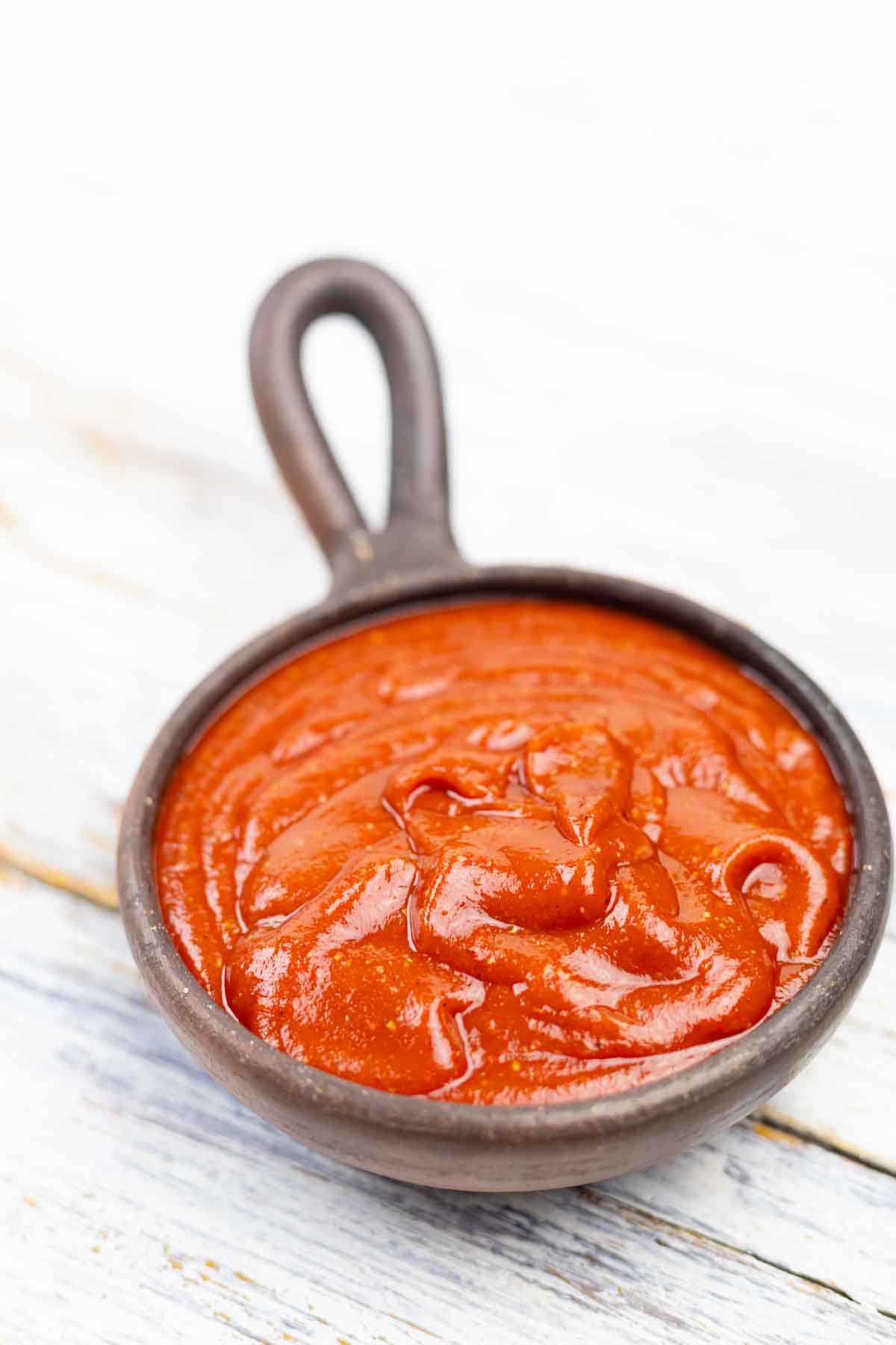 BBQ sauce in a bowl on a wooden table.