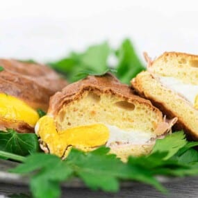 A plate with halved pastries filled with egg, surrounded by fresh parsley.