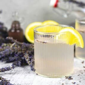 Two glasses of lavender lemonade are garnished with lemon slices.