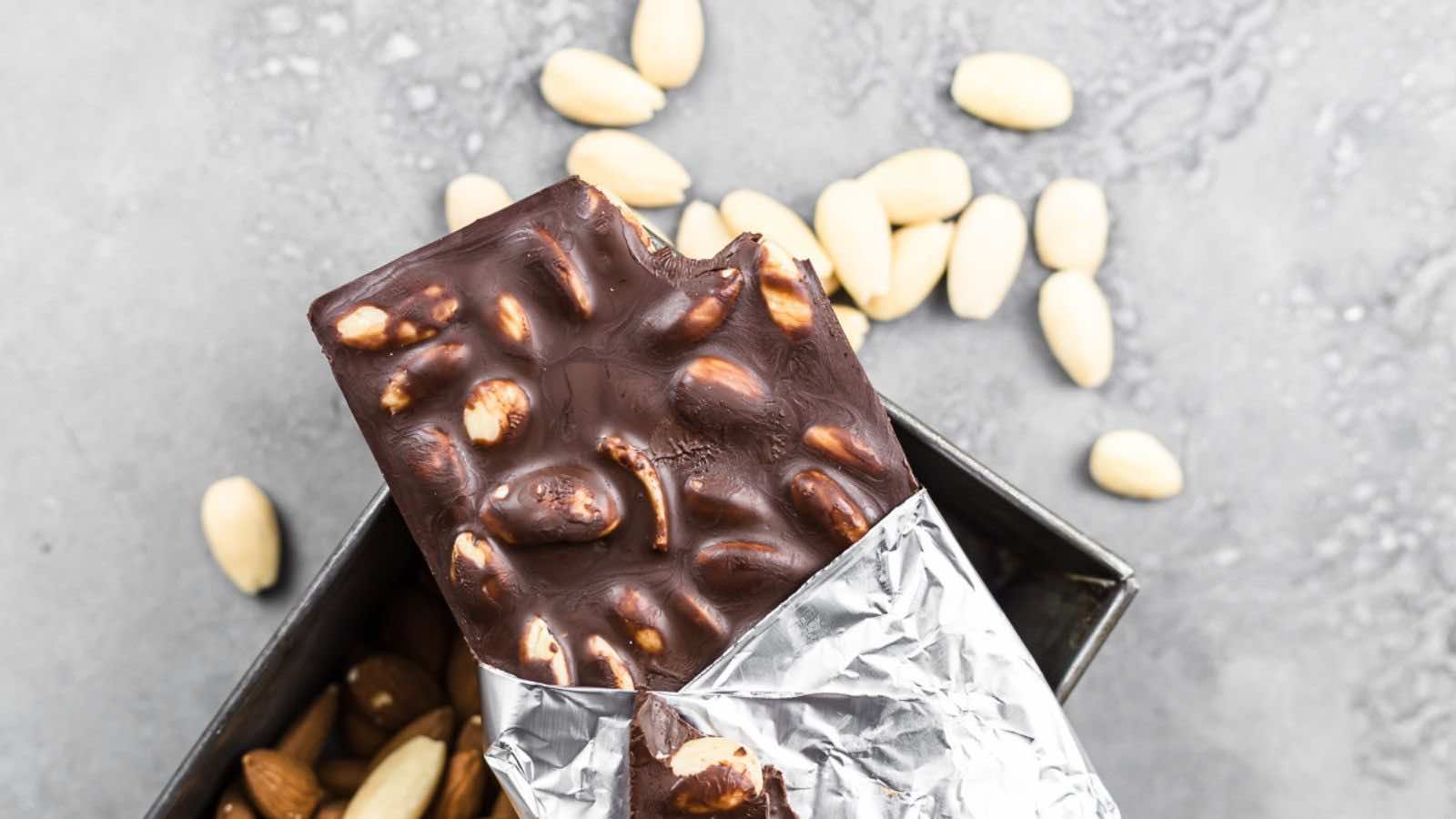 Chocolate bar with almonds partially unwrapped.