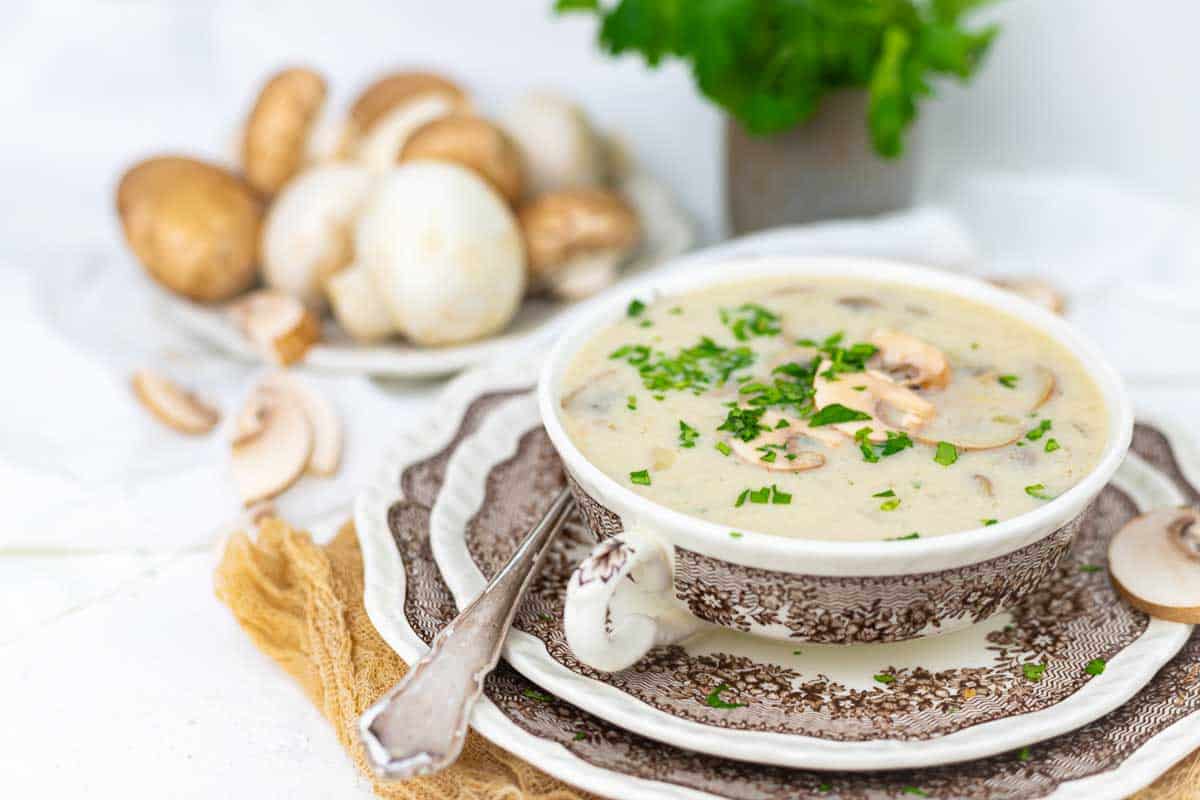 A bowl of mushroom soup garnished with chopped parsley.