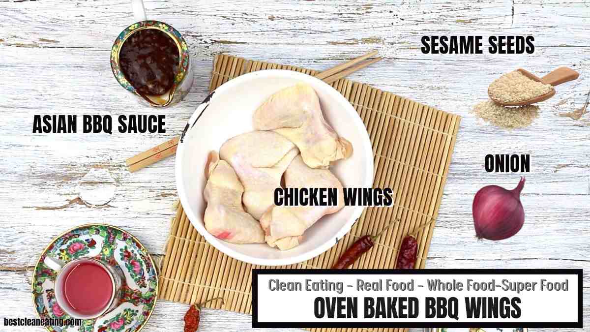 Top-down view of raw chicken wings in a bowl, surrounded by ingredients including Asian BBQ sauce, sesame seeds, and a red onion, labeled for an oven baked BBQ wings recipe.