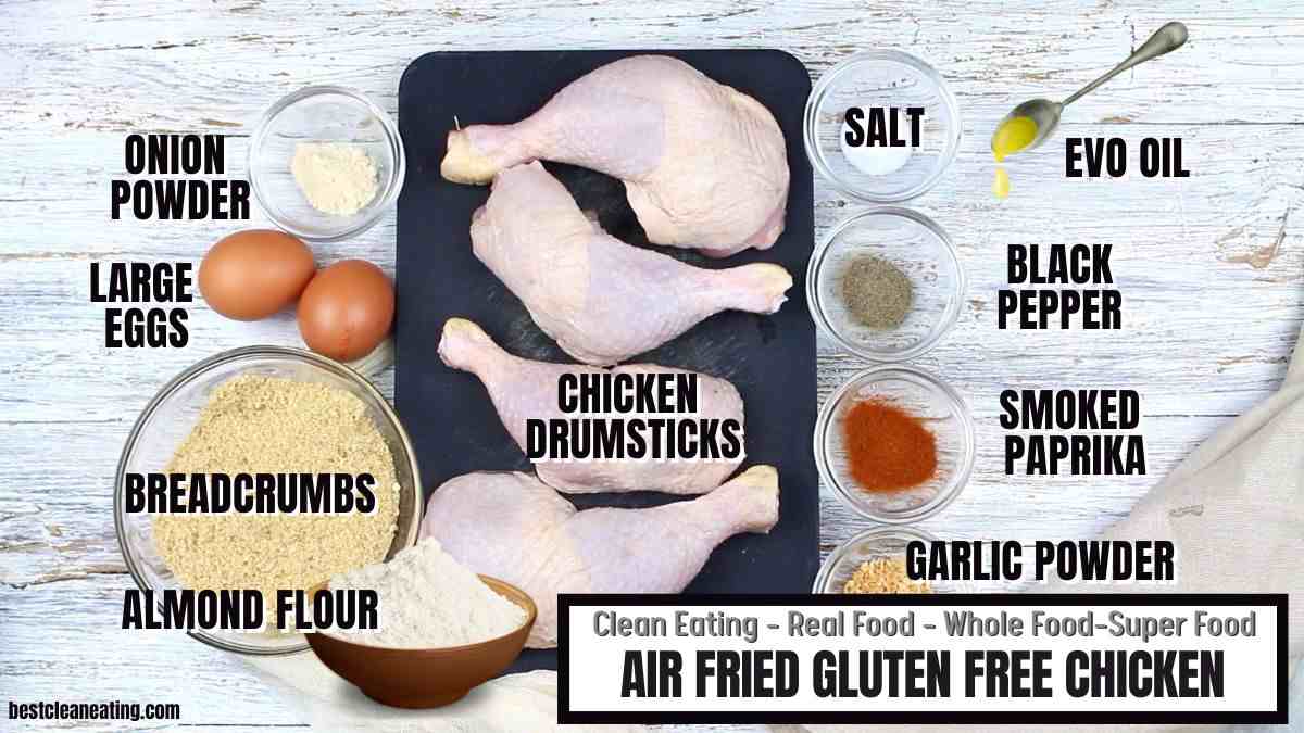 A flat lay of ingredients for air fried gluten free chicken, including chicken drumsticks, eggs, breadcrumbs, almond flour, spices, salt, and olive oil.