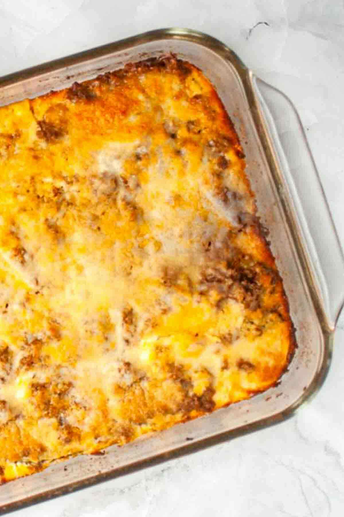 Golden cheesy zucchini casserole in glass dish.