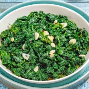 Kale dish placed on textured blue surface.