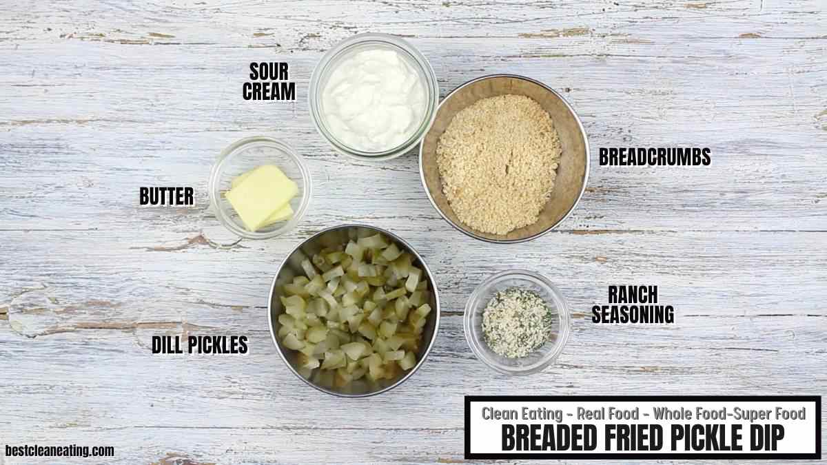 Five bowls containing sour cream, breadcrumbs, butter, chopped dill pickles, and ranch seasoning, labeled as ingredients for breaded fried pickle dip, displayed on a white wooden surface.