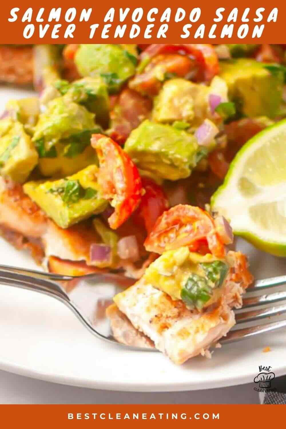 A plate with a piece of salmon topped with avocado salsa, cherry tomatoes, red onion, cilantro, and a lime wedge on the side.