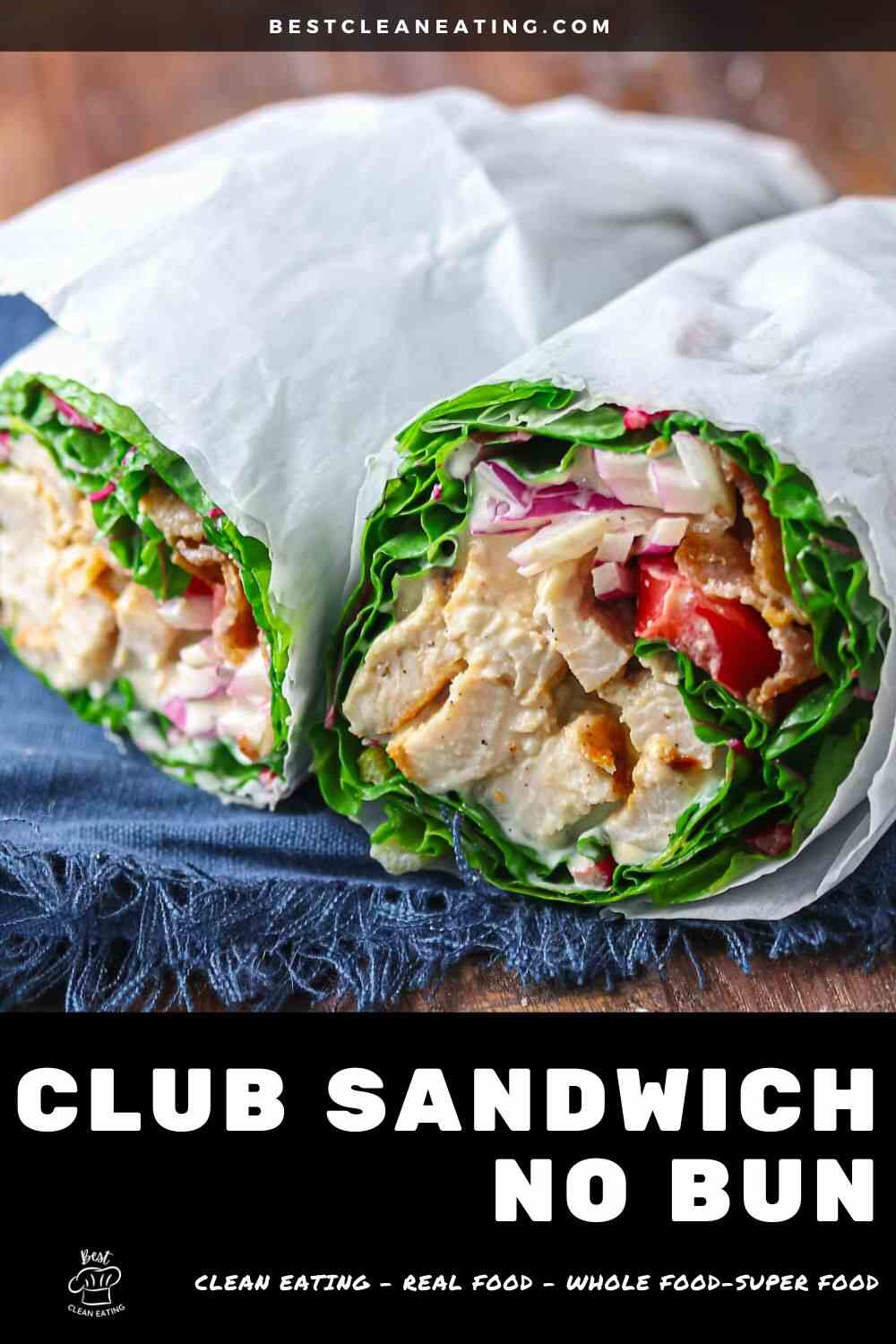 Two club sandwich wraps filled with chicken, lettuce, tomato, and red onion, wrapped in paper, served without bread on a dark surface.