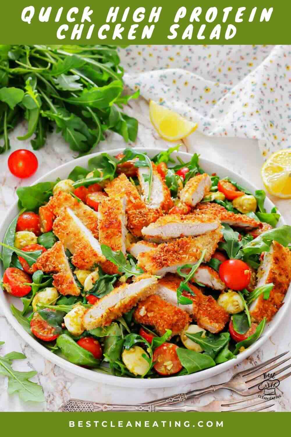 A bowl of salad with breaded chicken strips, cherry tomatoes, avocado pieces, and leafy greens, garnished with lemon wedges and fresh herbs.