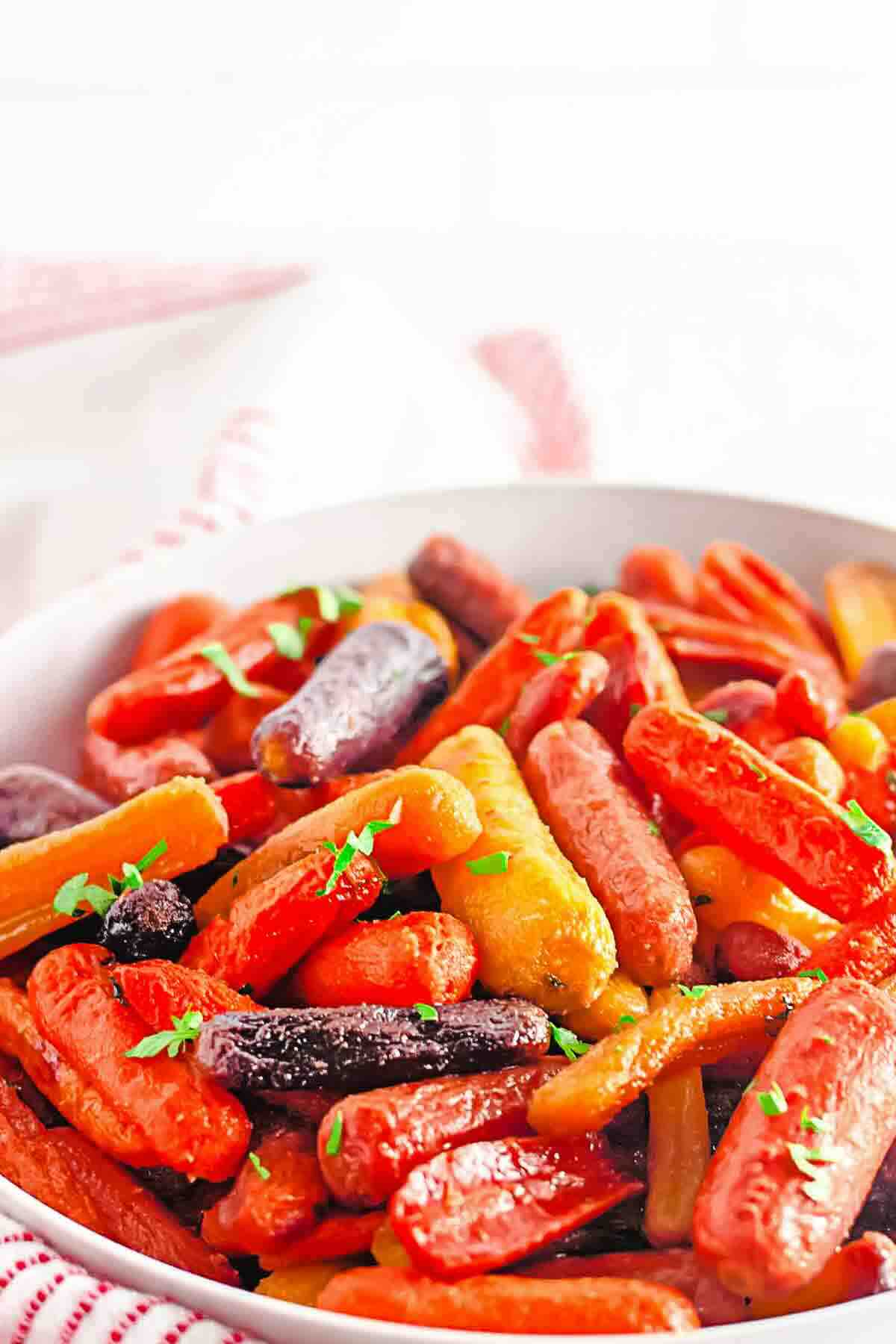 A bowl of roasted baby carrots in various colors, garnished with chopped herbs.