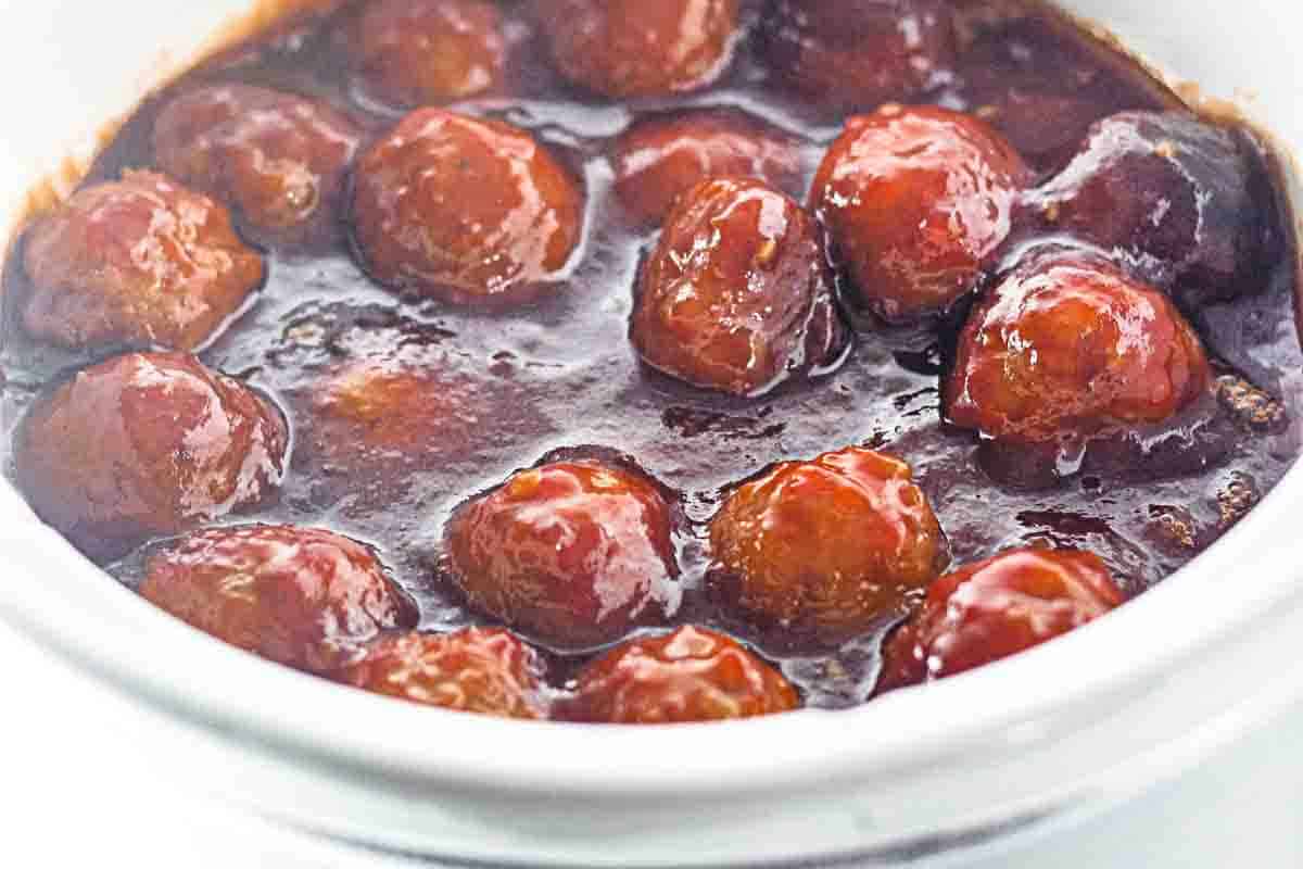 Meatballs coated in a thick, glossy brown sauce served in a white bowl.