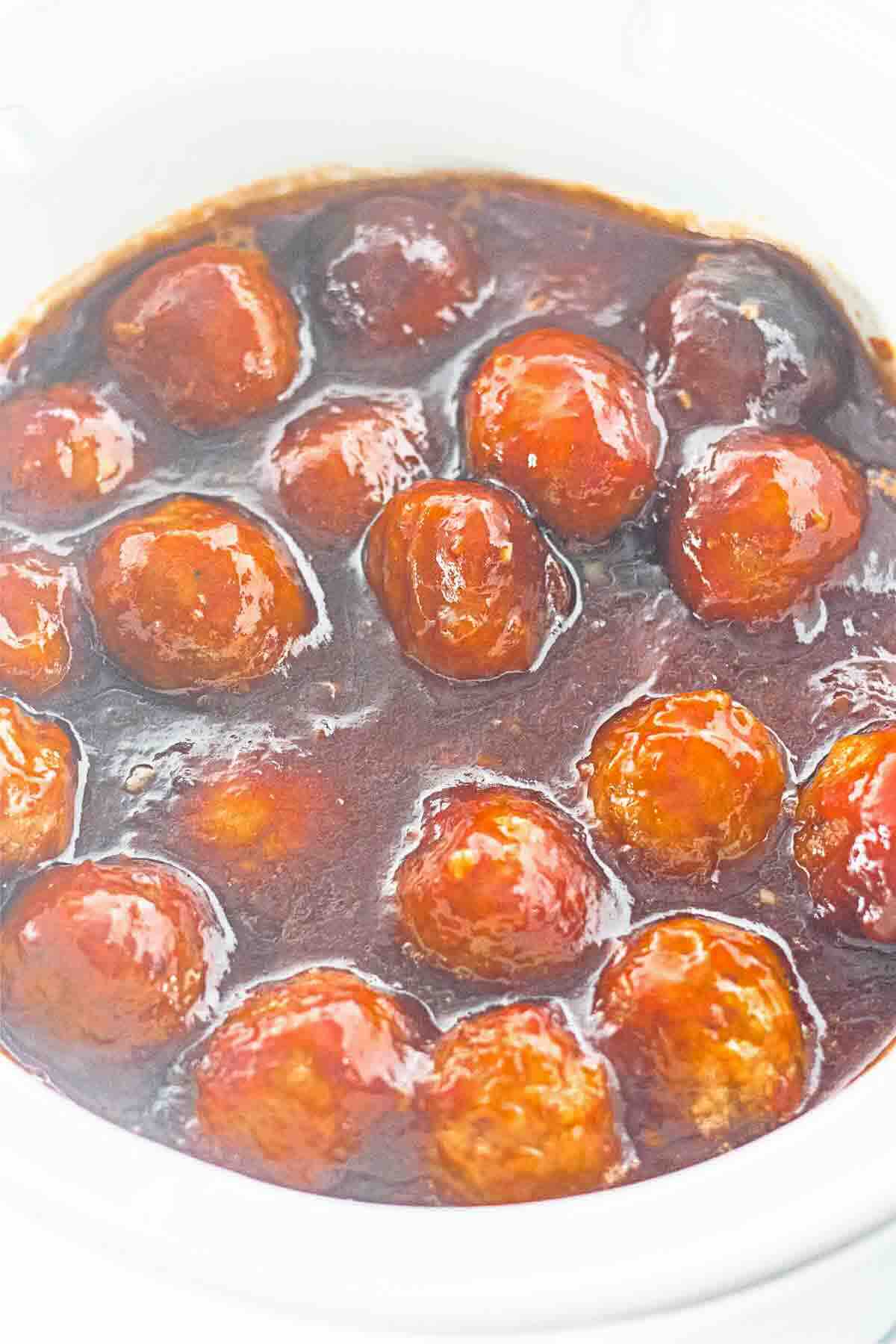 Meatballs coated in a glossy brown sauce, served in a white bowl.
