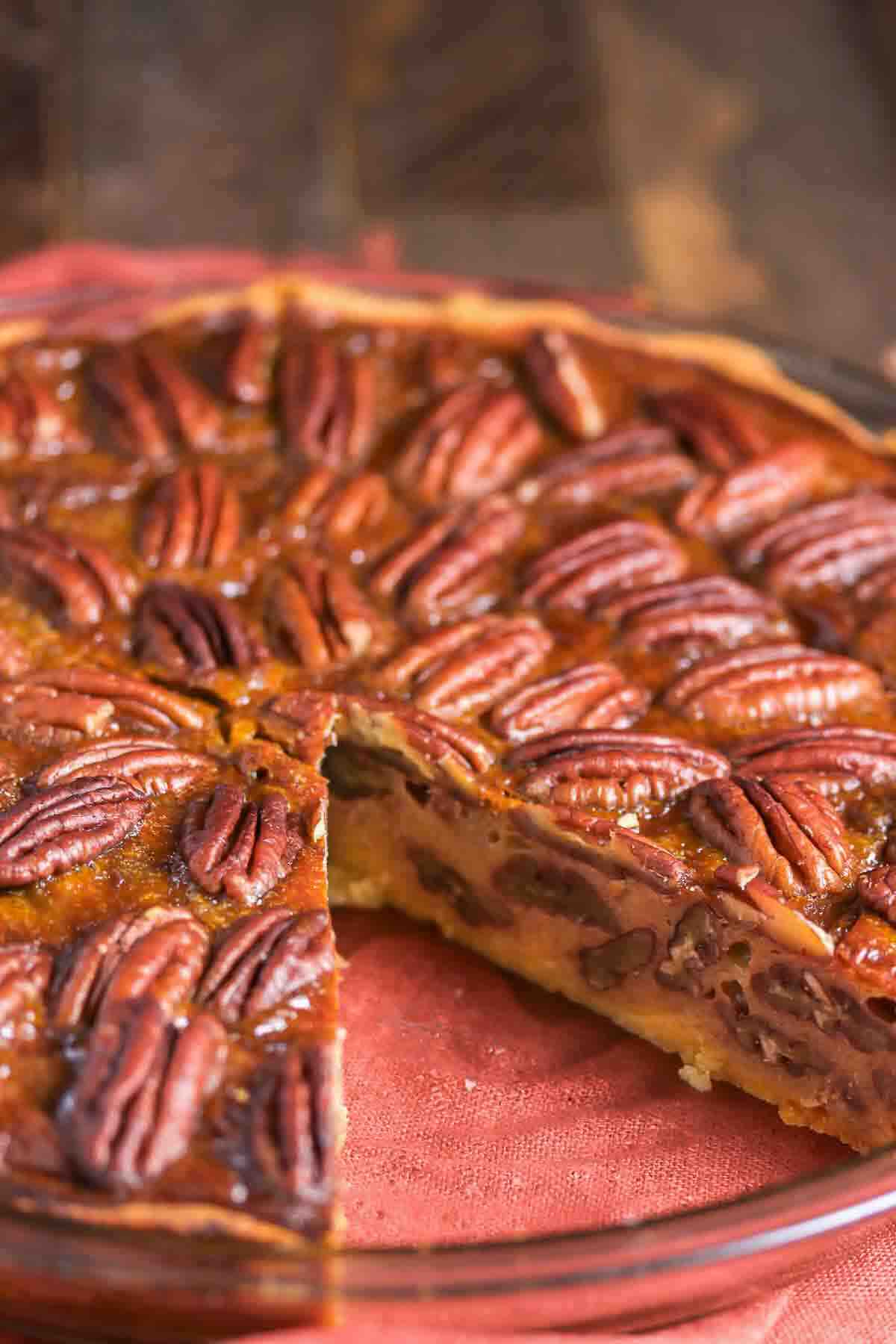 Pecan pie in a glass dish with one slice removed.