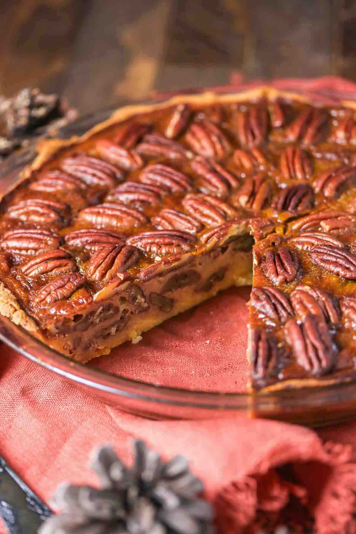 A pecan pie in a glass dish with one slice removed.