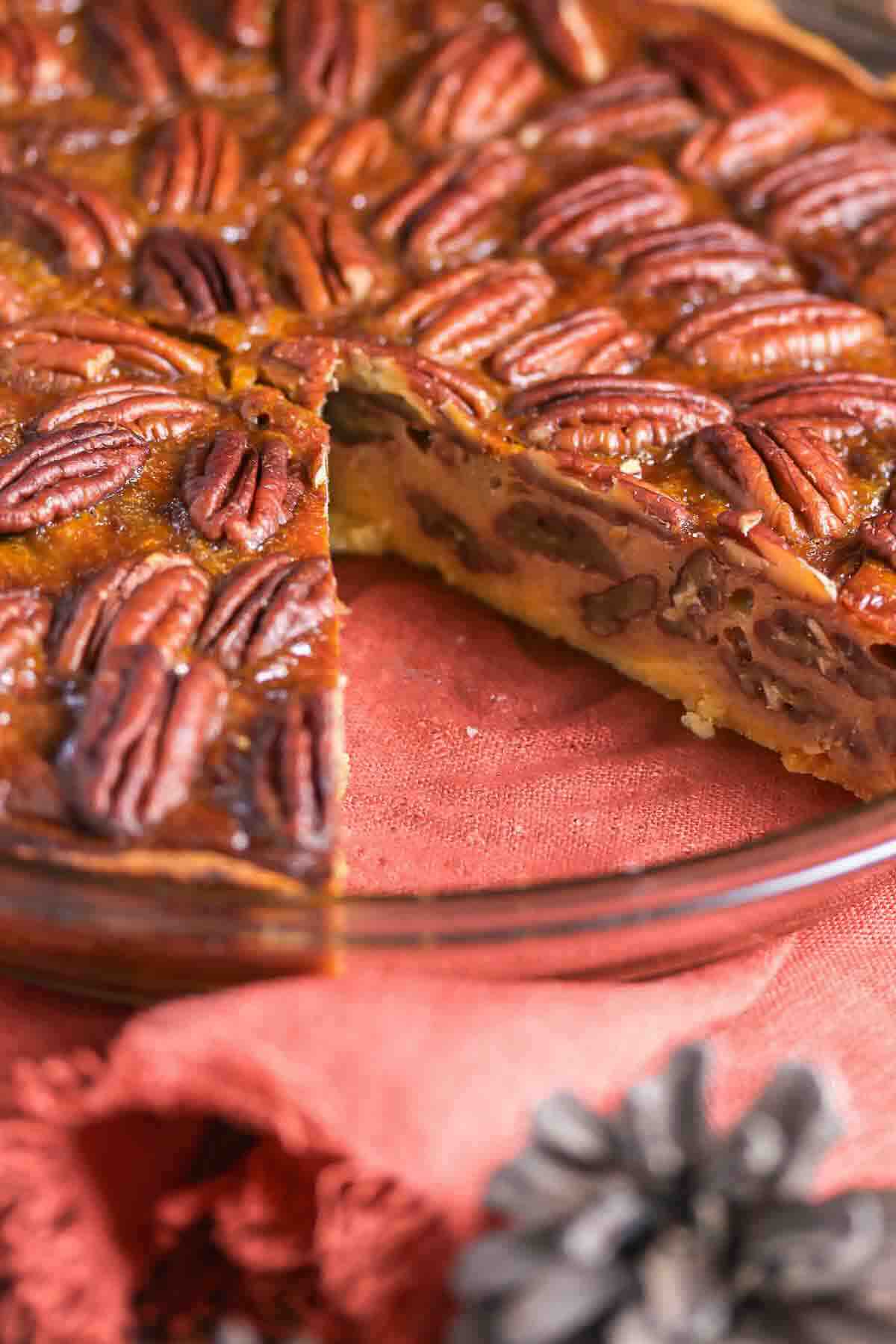 Pecan pie in a glass dish with a slice removed.